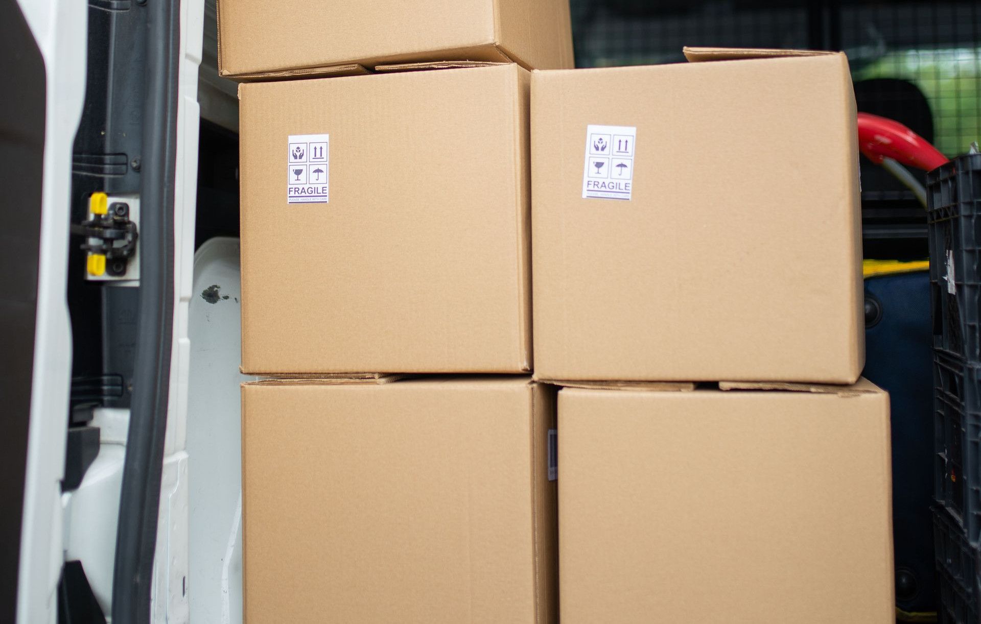 Stacked cardboard boxes inside an open delivery van, ready for shipment.