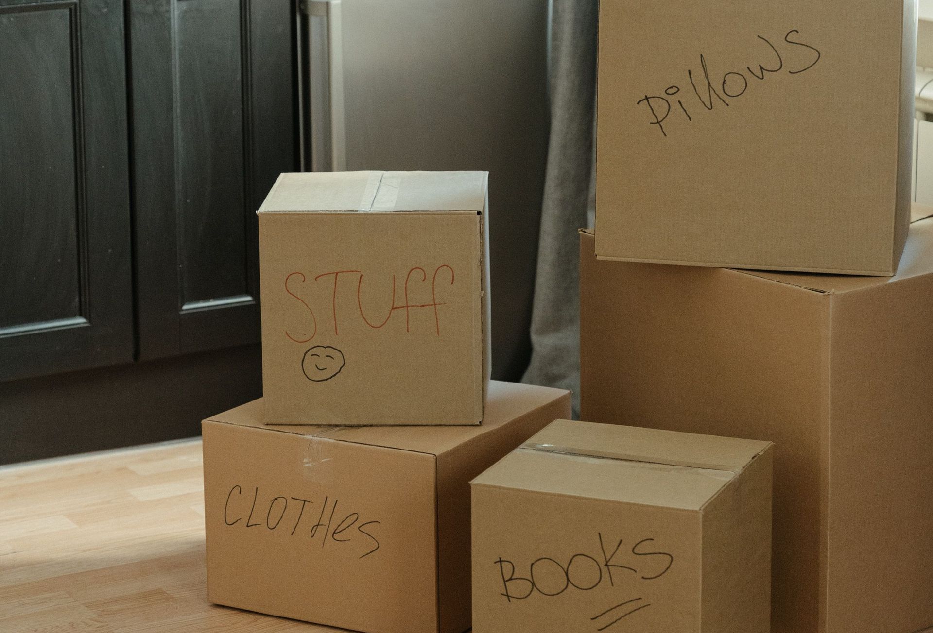 Cardboard boxes labeled with contents in a kitchen, suggesting a recent move-in.